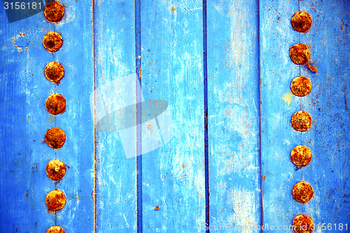 Image of dirty stripped paint in the blue wood door and rusty 