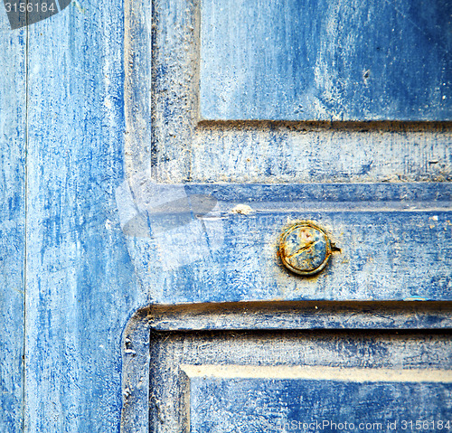 Image of stripped paint in the blue wood door and rusty nail