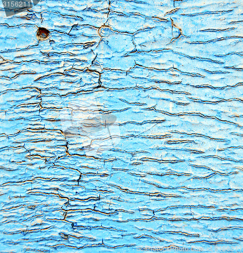 Image of dirty stripped paint in the blue wood door and rusty nail