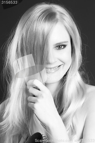 Image of Beautiful Smiling Blond Woman Grooming Brushing Her Hair