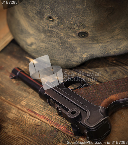 Image of pistol Parabellum and vintage German soldier helmet