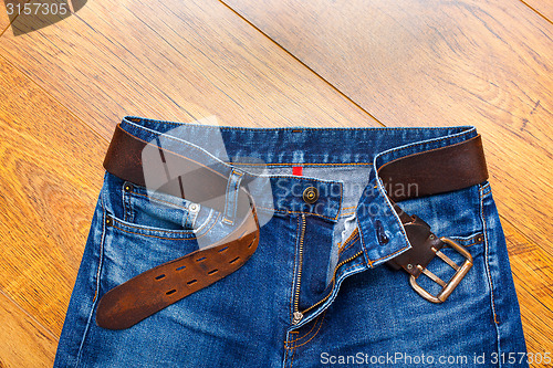 Image of Aged blue jeans with a leather belt