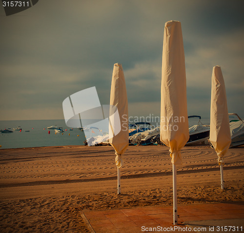 Image of beach, folded umbrellas, early morning