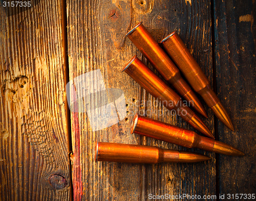 Image of five rifle cartridges on wooden surface