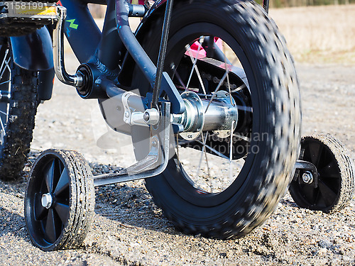 Image of Bicycle with supporting wheels stuck in loose gravel