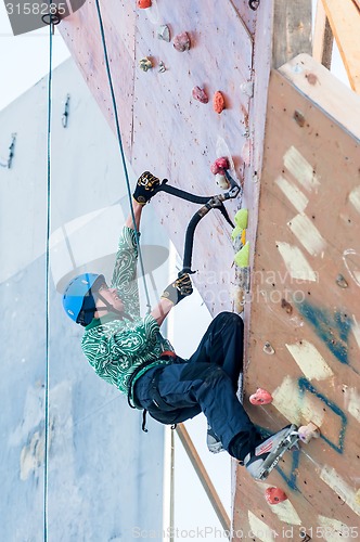 Image of Man climbs upward on ice climbing competition