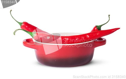 Image of Three red chili peppers in saucepan