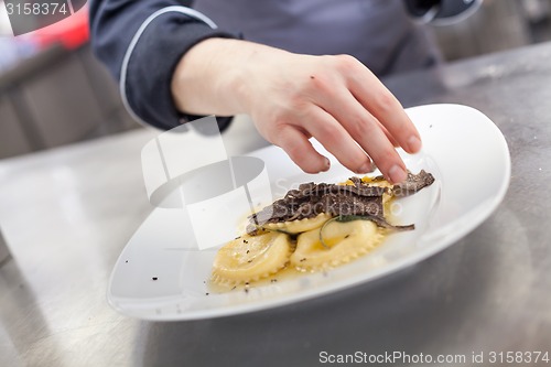 Image of Chef grating truffle mushroom onto ravioli pasta