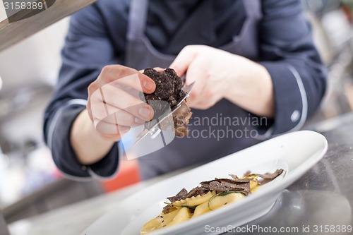 Image of Chef grating truffle mushroom onto ravioli pasta