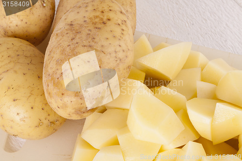 Image of Whole Potatoes and Chopped Pieces on Cutting Board