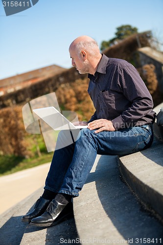 Image of Man sitting on a bench using a laptop