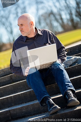 Image of Man sitting on a bench using a laptop