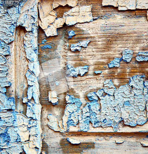 Image of dirty stripped paint in the blue wood door and rusty nail