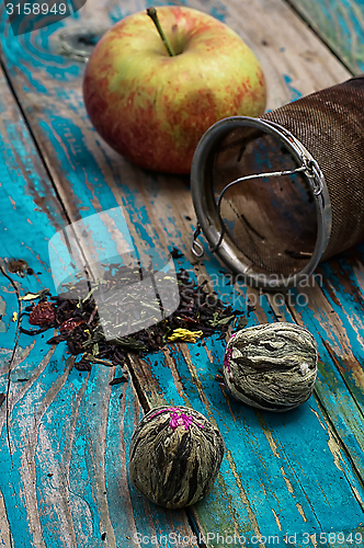 Image of tea leaves and red apple on wooden background