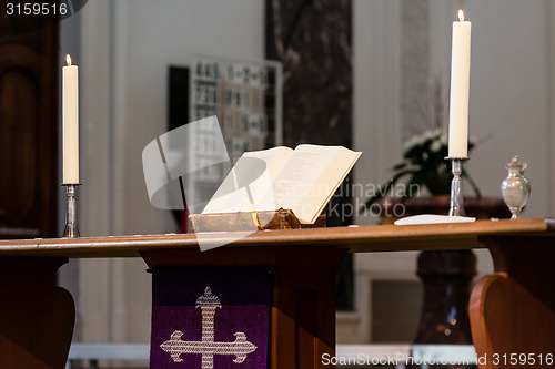 Image of Open Bible and candles on the altar of a church