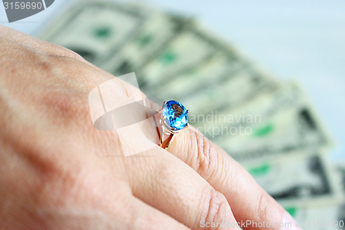 Image of Hand with topaz on the finger and dollars