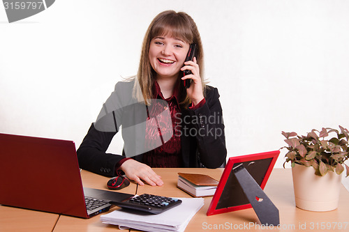 Image of The girl behind the office desk laughing with handset