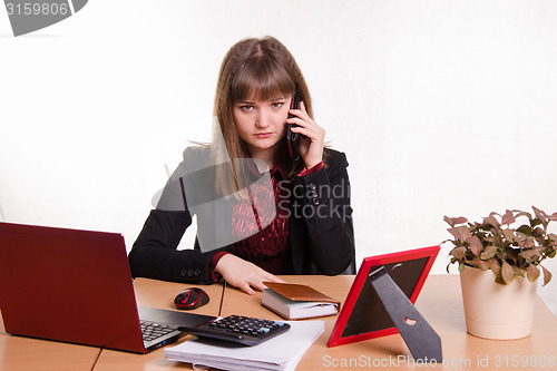 Image of The girl behind office table talks on phone