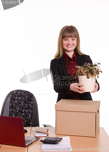 Image of Girl office about desktop keeps indoor flower in pot