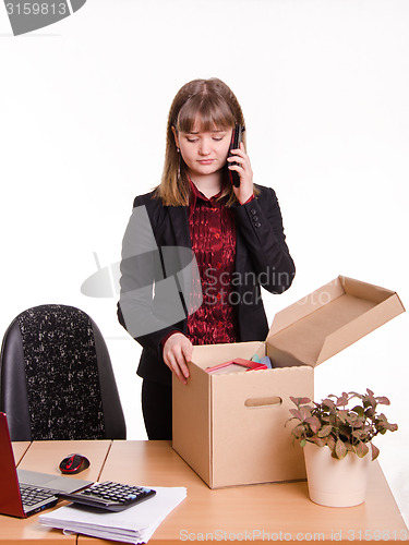 Image of Girl in office examines personal things and calling on phone