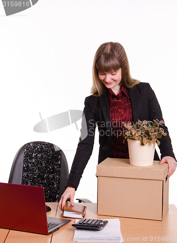 Image of Adopted at work in office girl puts things out of box