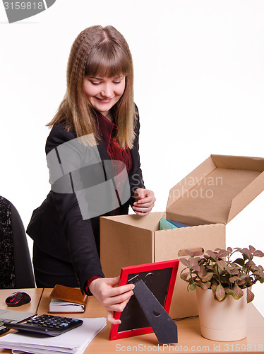 Image of Girl puts a photo frame on desktop in office