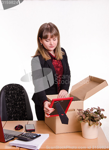 Image of Girl in office collects, parses personal belongings a box