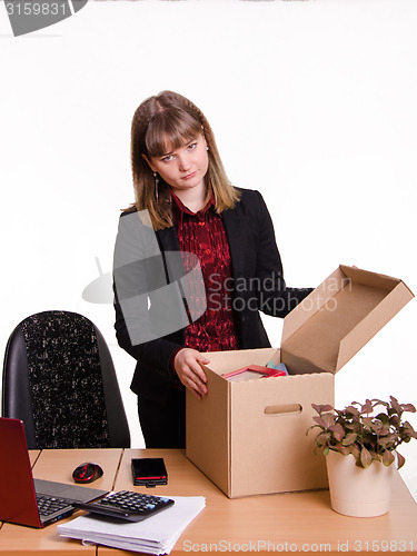 Image of Dismissed girl in office near table collects personal belongings a box