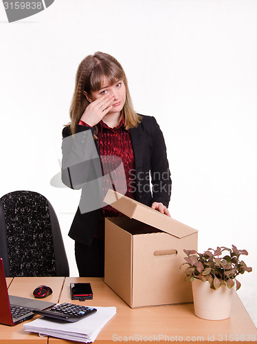 Image of Dismissed girl in office wipes tears and collects things