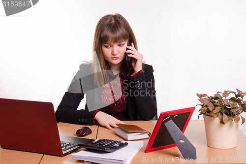 Image of girl behind office desk on phone listening to a friend