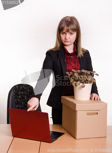 Image of Dismissed girl in office collects things and closes laptop