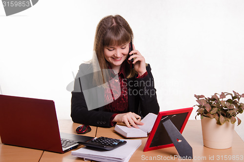 Image of The girl behind the desk office conducts a dialogue by phone