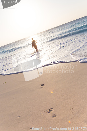 Image of Woman running on the beach in sunset.