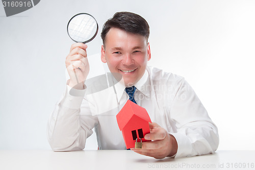 Image of Man with a magnifying glass and paper house