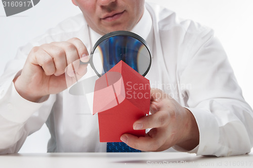 Image of Man with a magnifying glass and paper house