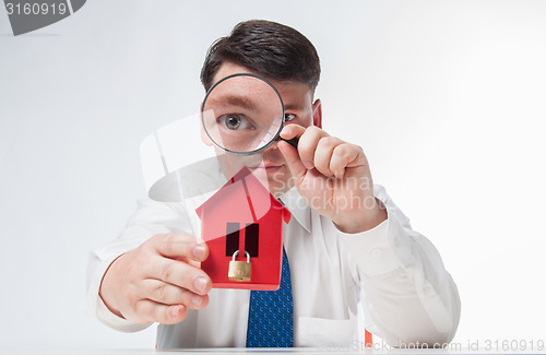 Image of Man with a magnifying glass and paper house