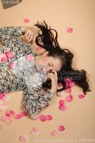 Image of atractive brunette girl lying on beige background