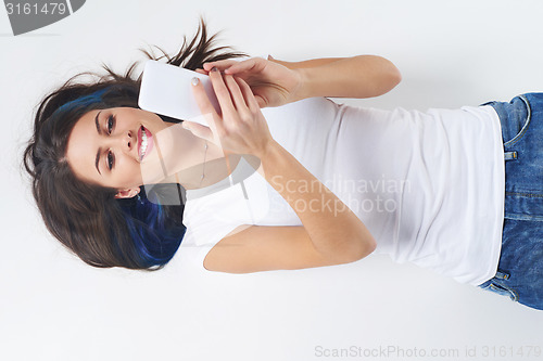 Image of Woman lying on her back and using phone