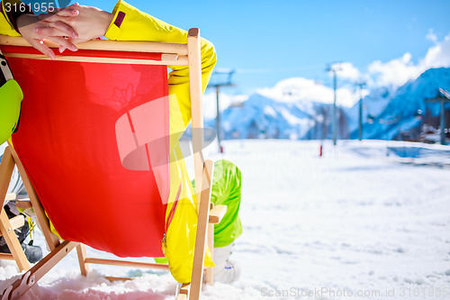 Image of Women at mountains in winter lies on sun-lounger