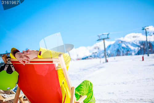 Image of Women at mountains in winter lies on sun-lounger