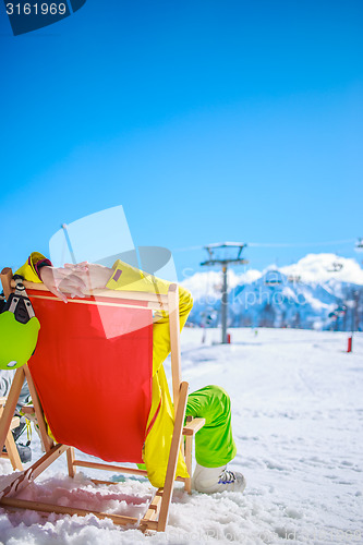 Image of Women at mountains in winter lies on sun-lounger