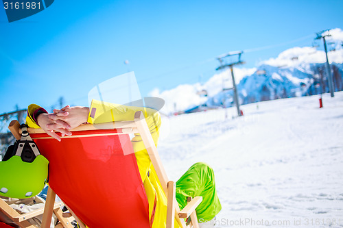 Image of Women at mountains in winter lies on sun-lounger