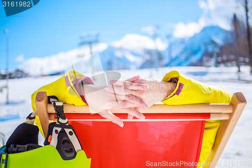 Image of Women at mountains in winter lies on sun-lounger