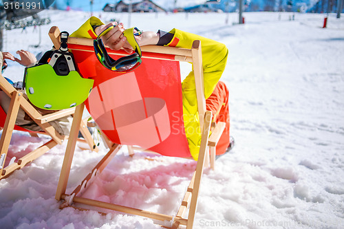 Image of Women at mountains in winter lies on sun-lounger