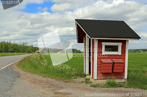 Image of Landscape of Red Wooden Bus Stop Shelter with Two Mail Boxes