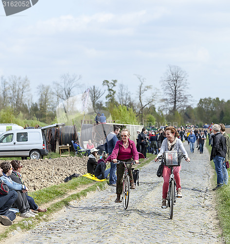 Image of Two Casual Women Cycling on a Cobblestoned Road