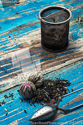 Image of variety of dry tea leaves in jade stacks on wooden background