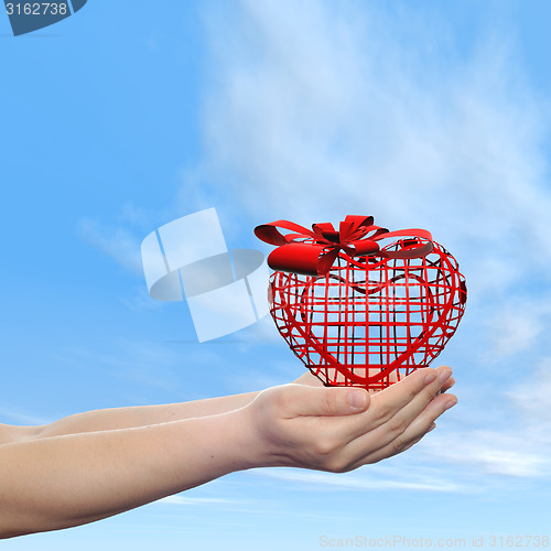 Image of Conceptual human hand with heart and blue sky