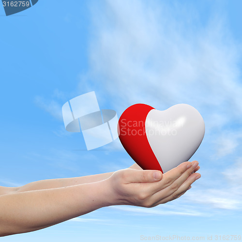Image of Conceptual human hand with heart and blue sky