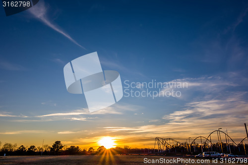 Image of sunset over field and amusement park in distance